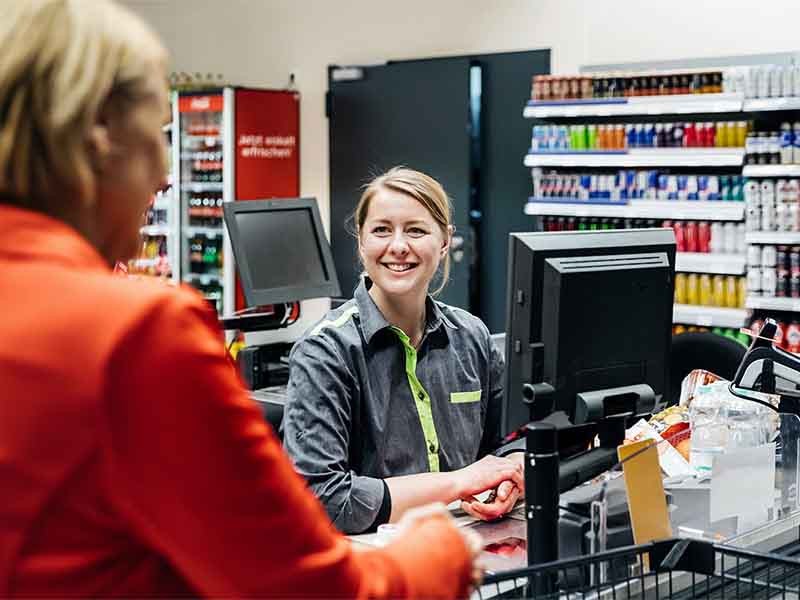 Cashier and customer communicating while buying groceries at a supermarket store